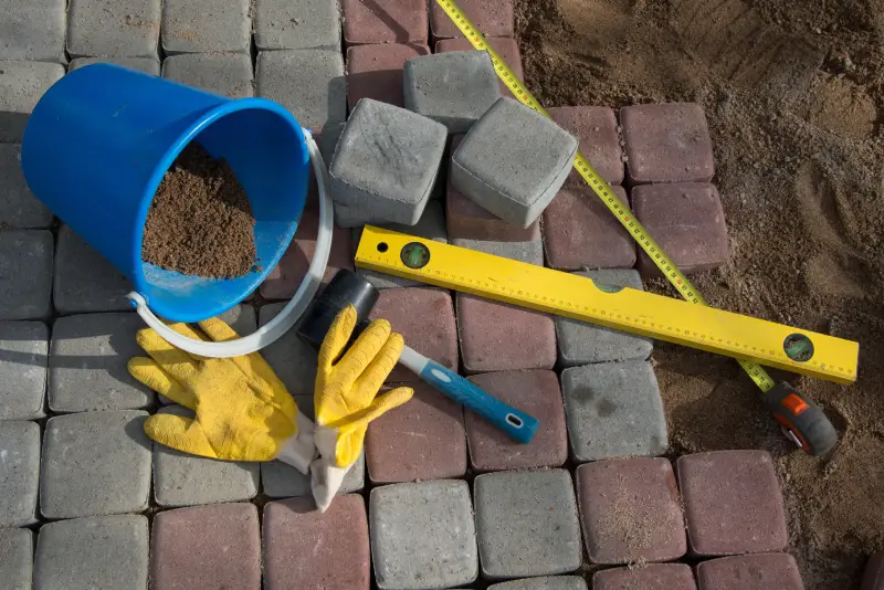 Pavement details stone blocks rubber hammer level gloves and tape measure